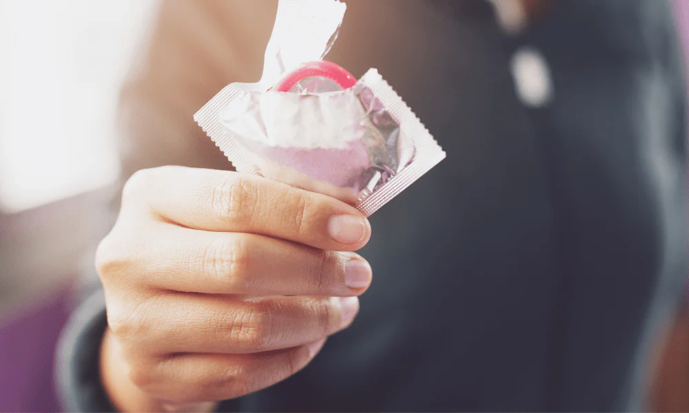 Sex nach Magenverkleinerung Op: Wann und wie? Hand hält Kondom in Verpackung